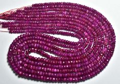 purple seed beads are lined up on a white surface