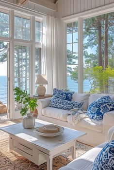 a living room filled with furniture and large windows overlooking the water in front of it