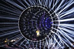 a woman standing in front of a large mirror ball on top of a stage at night