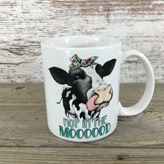 a white coffee mug with a black and white cow on it's face that says, not in the mood