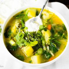 a white bowl filled with vegetable soup and sour cream