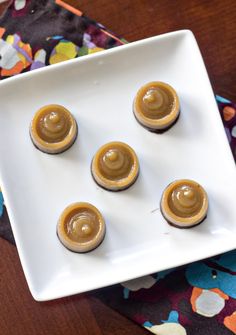 four small cupcakes on a white plate with peanut butter frosting in the middle