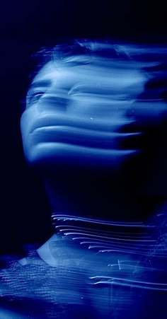 a blurry photo of a person's head and neck in the dark blue light