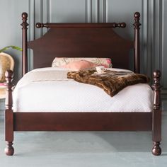 a bed with wooden headboard and foot board is shown in front of a gray wall