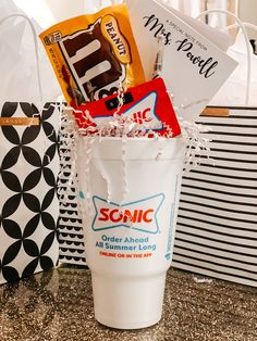 a cup filled with candy and other items on top of a counter next to bags