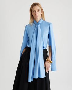 The Lavallière Blouse in Airy Blue by Patou features a stand collar with removable, oversized bow and JP-engraved mother of pearl buttons. The sleeves are an oversized, raglan construction with buttoned French cuffs. 100% Organic Cotton Made in Madagascar BL0340017636B Jean Patou, French Cuff, Denim Trousers, Cynthia Rowley, Mother Of Pearl Buttons, Pearl Buttons, Cotton Blouses, Thom Browne, Natural Linen