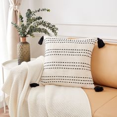 a couch with two pillows on it and a plant in a vase next to it