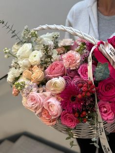 a woman holding a basket full of pink and white flowers