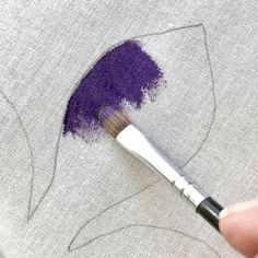 someone is using a brush to paint the design on a piece of fabric that has been stitched