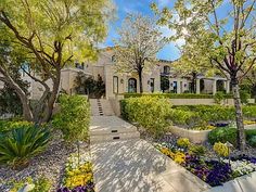 a large house surrounded by trees and flowers