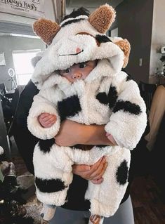 a woman holding a baby wearing a cow costume