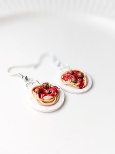 two small white plates with some food on them and silver earwires hanging from them