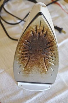 a close up of an iron on a white table cloth with some wires in the background