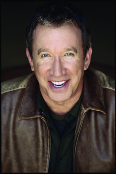 a close up of a person wearing a brown leather jacket and smiling at the camera