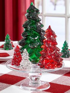 small glass christmas trees are sitting on a table with red and white checkered cloth