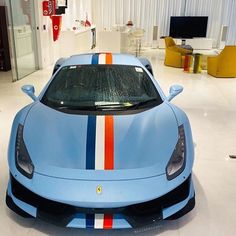 a blue sports car with red, white, and blue stripes on the hood in a showroom