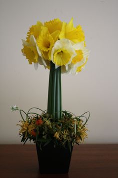 yellow and white flowers are in a black vase