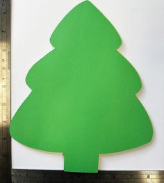 a paper cut out of a green christmas tree on top of a piece of white paper