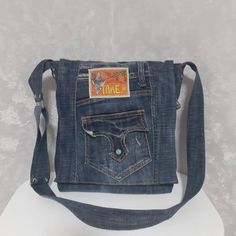 a denim bag with the word time printed on it's front pocket and an adjustable strap