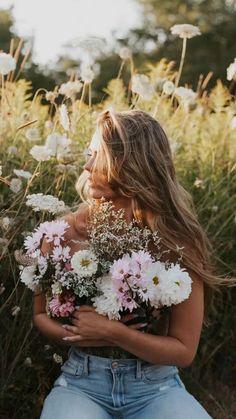 a woman sitting in a field with flowers on her chest and arms around her body