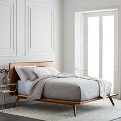 a bed sitting on top of a white rug next to a wooden headboard and foot board