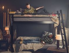 two men laying on top of bunk beds in a room with other furniture and decor