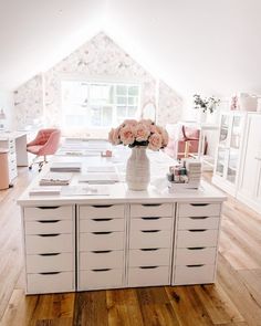 a room with white furniture and flowers in the vase on the top of the table