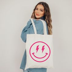 "Oh yesss, this awesome preppy aesthetic tote bag with Smiley Face with lightning eyes print is definitely a real eye-catcher! Just fun to use as a school bag or reusable bag. It will hold all of your preppy stuff. Just perfect! Yes we know, this bag is a real everyday musthave and very fashionable. Love yourself and buy one for you and your best friend or anyone else that loves happy and smiley emojis! * Good to know: Kindly note that the bag has no extra pockets or zipper closure * Material: Sustainable 100% cotton canvas * Color tote: Natural or black * Size: The tote measures 15.0\"- 38.0 cm in width and 16.5\"- 42.0 cm in heigth to be carried on your shoulder or hand, its capacity is 10L. Kindly note that slight differences in size are possible * Note: The design on each bag is hand-p Trendy Rectangular Canvas Bag For Back To School, Trendy Tote Shoulder Bag For Back To School, Trendy Graphic Print Shoulder Bag For Everyday, Trendy Back To School Shoulder Canvas Bag, Trendy Everyday Bag For Back To School, Trendy Pink Bags With Graphic Print, Trendy White Shoulder Bag With Graphic Print, Trendy Rectangular Canvas Bag With Graphic Print, Pink Graphic Print Tote Bag