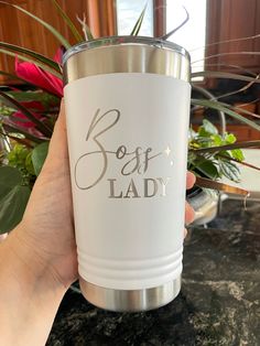 a person holding up a white cup with the words soft lady on it in silver lettering