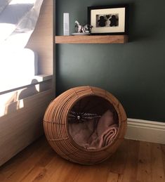 a cat bed sitting on top of a hard wood floor next to a wooden shelf