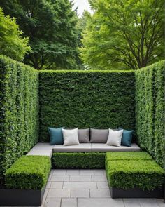 an outdoor seating area with green hedges and pillows