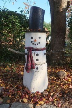 a snowman made out of logs with a top hat and scarf tied around it