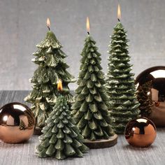 three small christmas trees are sitting next to each other with lit candles in the middle