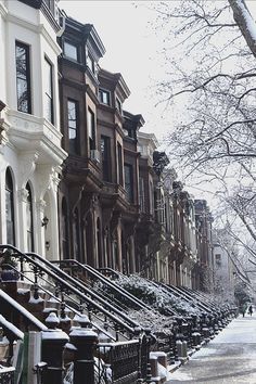 a row of browns and white townhouses on a snowy day with snow covered sidewalks