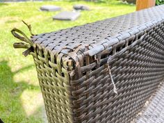 an empty wicker basket sitting on top of a wooden bench in the grass outside