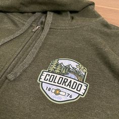 A hooded sweatshirt version of our 2023 best selling Woodland t-shirt, this Colorado hoodie is an awesome combination of organic outdoor colors and ColoradoCool's bold design style. Features a sweet outdoor Colorado landscape, big "COLORADO" text, Colorado's established date and a nice subtle topo map in the background. The smaller design on the front is perfect for those who like to put into practice a little bit of that "mullet approach", business in the front and party in the back. Snag this Colorado Hoodie, Colorado Outfits, Colorado Landscape, State Of Colorado, Topo Map, Hoodie Green, Bold Design, Small Designs, Design Style