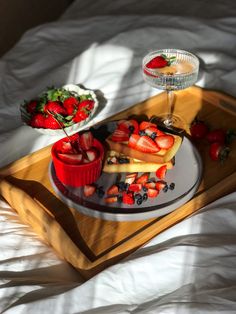 two plates with fruit on them sitting on a tray next to a glass of wine