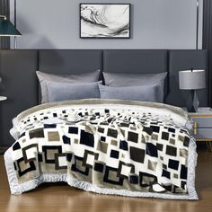 a bed with a black and white blanket on top of it next to two lamps