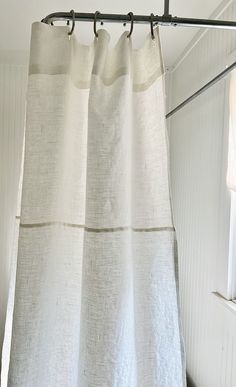 a white shower curtain hanging in front of a window