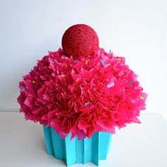 a red ball sitting on top of a blue vase filled with pink and purple flowers