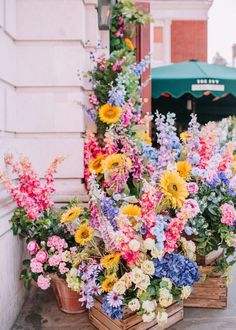 colorful flowers are arranged in wooden boxes on the sidewalk