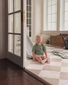 a little boy sitting on the floor in front of a door