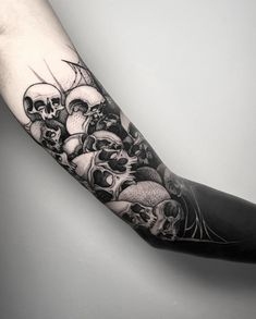 a man's arm with many skulls and bones tattoo on the left side of his arm