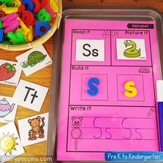 a pink tray filled with letters and numbers next to a bowl of colored pencils