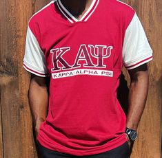 Show off your loyalty and pride for Kappa Alpha Psi fraternity with this stylish shirt. Made with high-quality materials, this shirt is perfect for any member  of the organization. The design prominently displays the fraternity's letters, ensuring that you will stand out and make a statement wherever you go. Whether you're attending a fraternity event or just want to show off your Greek pride, this Kappa Alpha Psi shirt is the perfect addition to your wardrobe. Fast Shipping & Processing: 1-2 da Collegiate Short Sleeve Shirt For College, Team-colored Cotton Tops With Embroidered Graphics, Collegiate Cotton Shirt For College, Fitted Short Sleeve Fan Gear Tops, Cotton Tops With Embroidered Logo For Fan Gear, Cotton Tops With Embroidered Graphics For Fan Gear, School Spirit Short Sleeve T-shirt With Embroidered Graphics, Red Varsity Top With Embroidered Logo, Varsity Style Top With Embroidered Graphics For Fan Gear