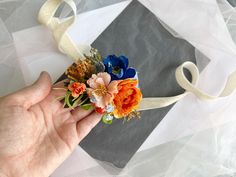 a person is holding some flowers in their left hand and ribbon on the other side