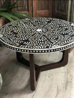 a black and white table sitting on top of a wooden floor next to a potted plant