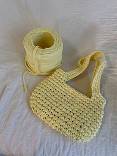 a crocheted bag and a spool of thread on a white bed sheet