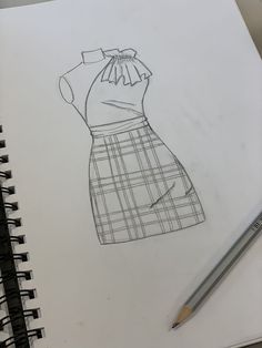 a drawing of a dress on paper next to a pencil