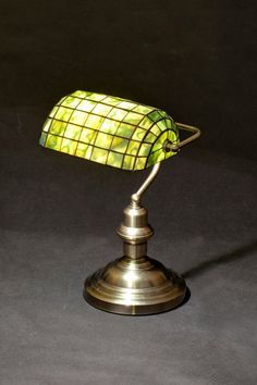 a green lamp sitting on top of a table next to a black wall and floor